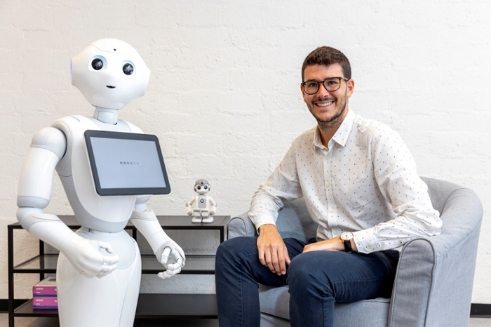Eduard Fosch-Villaronga sitting next to a white care robot